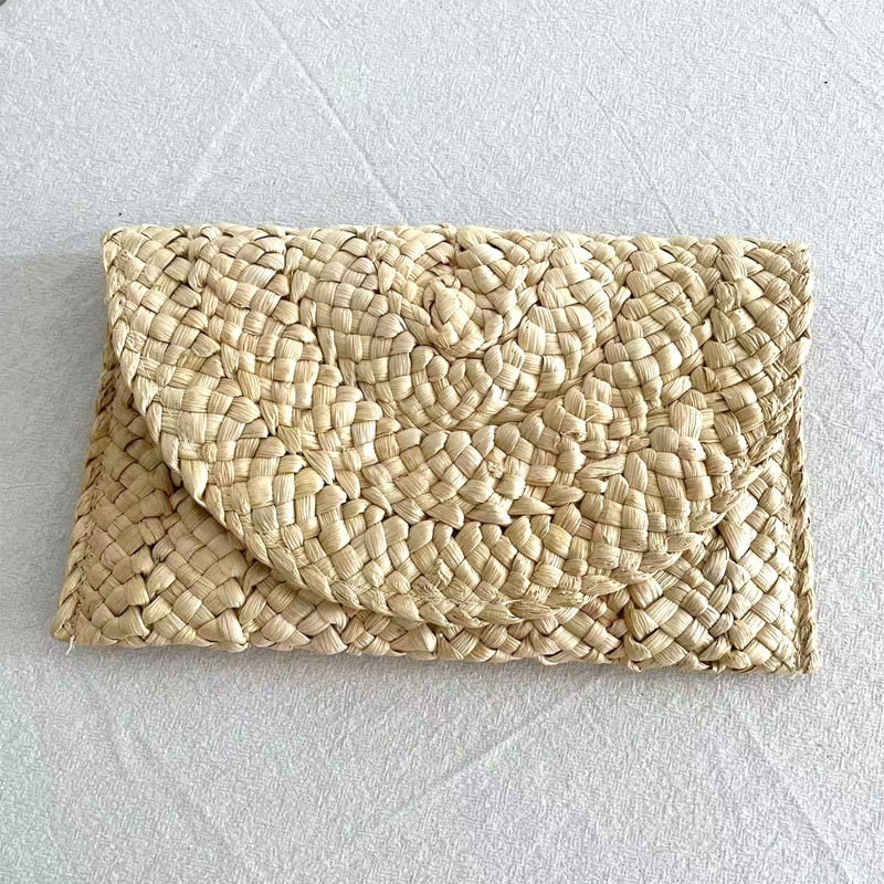 Small handmade woven straw clutch with a colorful pompom, offered in nine colors