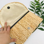 Small handmade woven straw clutch with a colorful pompom, offered in nine colors