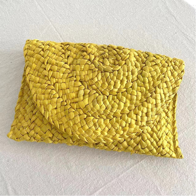 Small handmade woven straw clutch with a colorful pompom, offered in nine colors