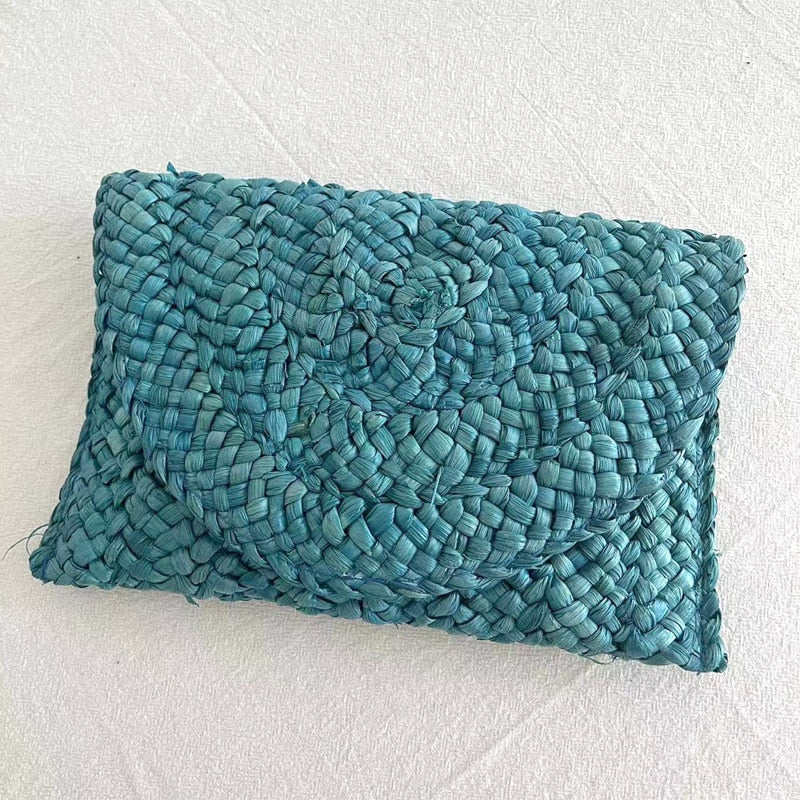 Small handmade woven straw clutch with a colorful pompom, offered in nine colors