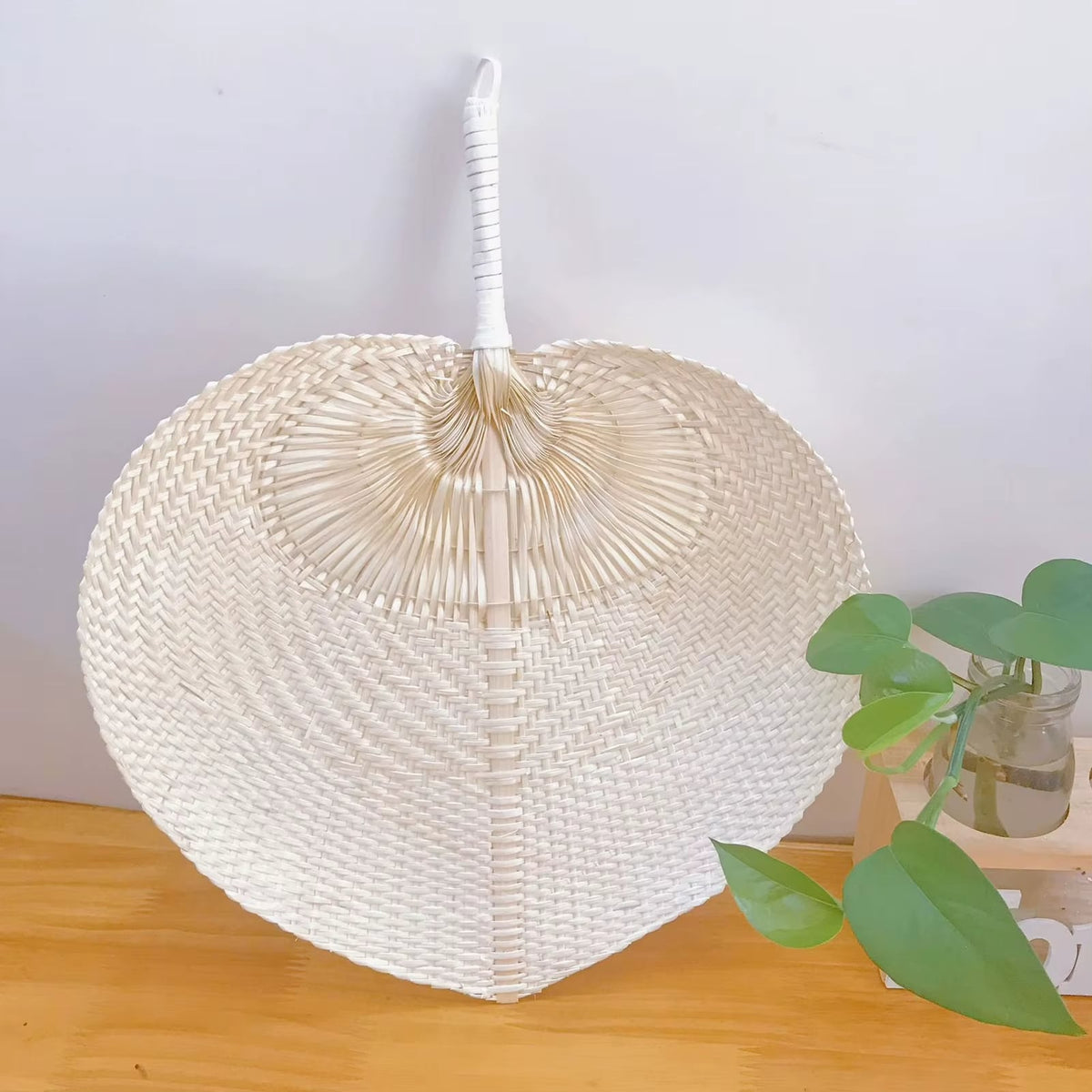 Cream heart shaped handwoven fan with a slim bamboo handle