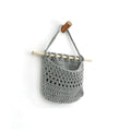 Gray open knit look wall basket hanging on a wooden dowel