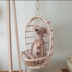 Round hanging rattan birdcage basket holding a plush toy