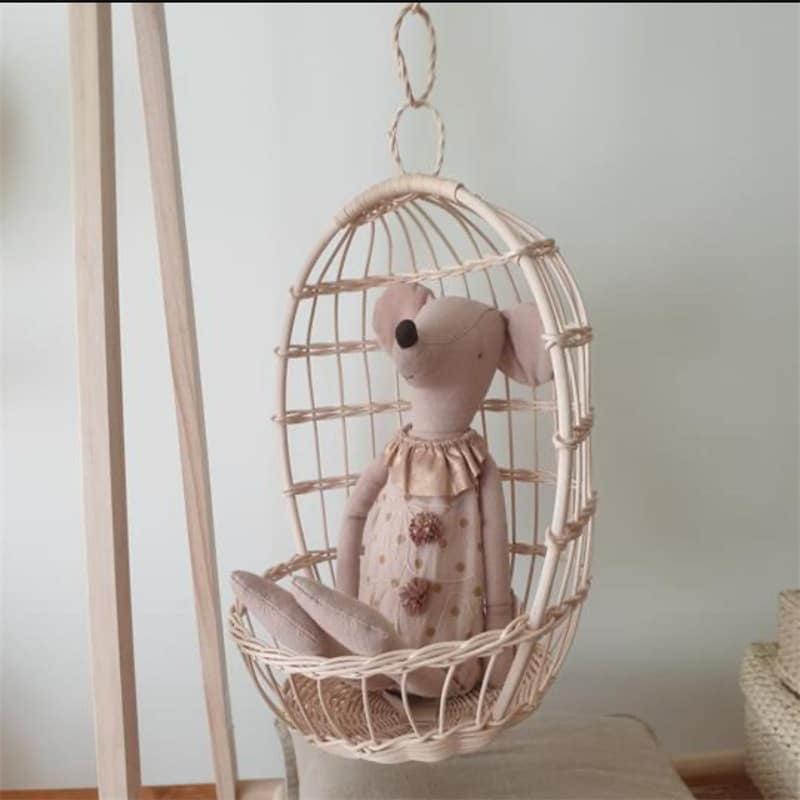 Round hanging rattan birdcage basket holding a plush toy