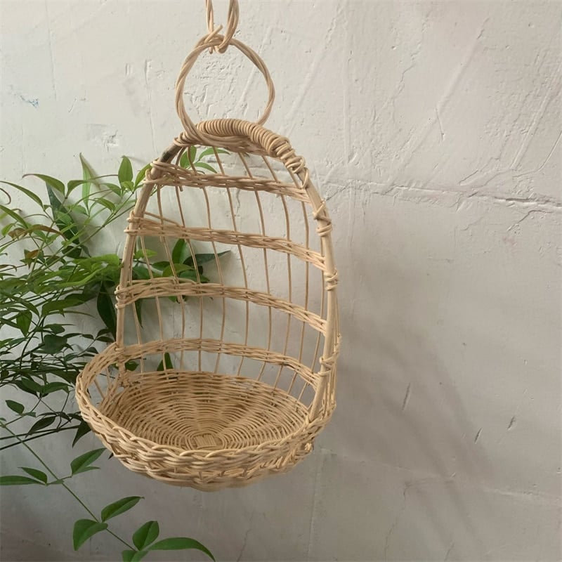Round hanging rattan birdcage basket holding a plush toy