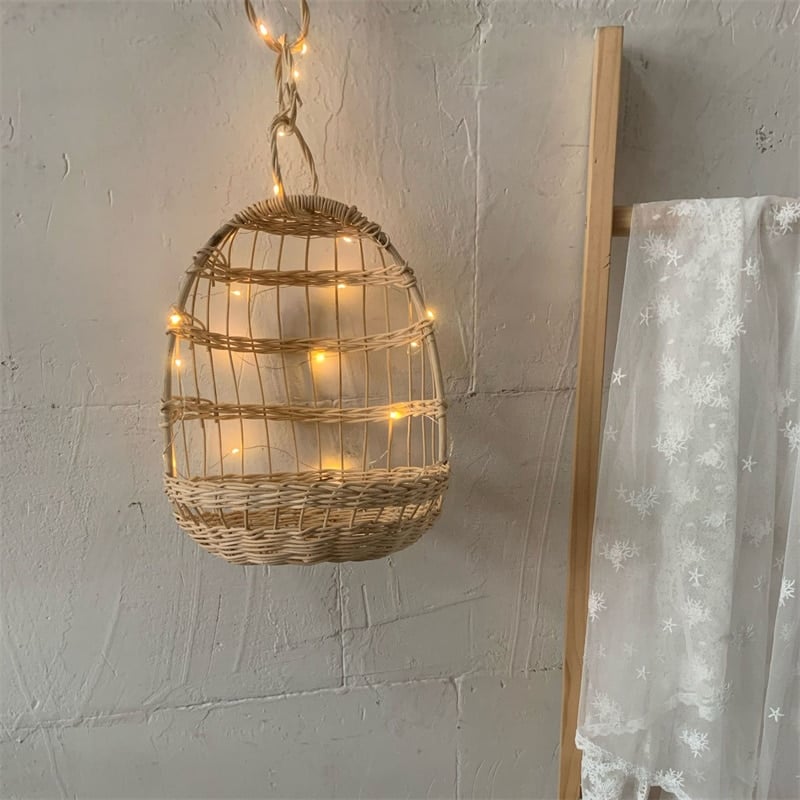 Round hanging rattan birdcage basket holding a plush toy