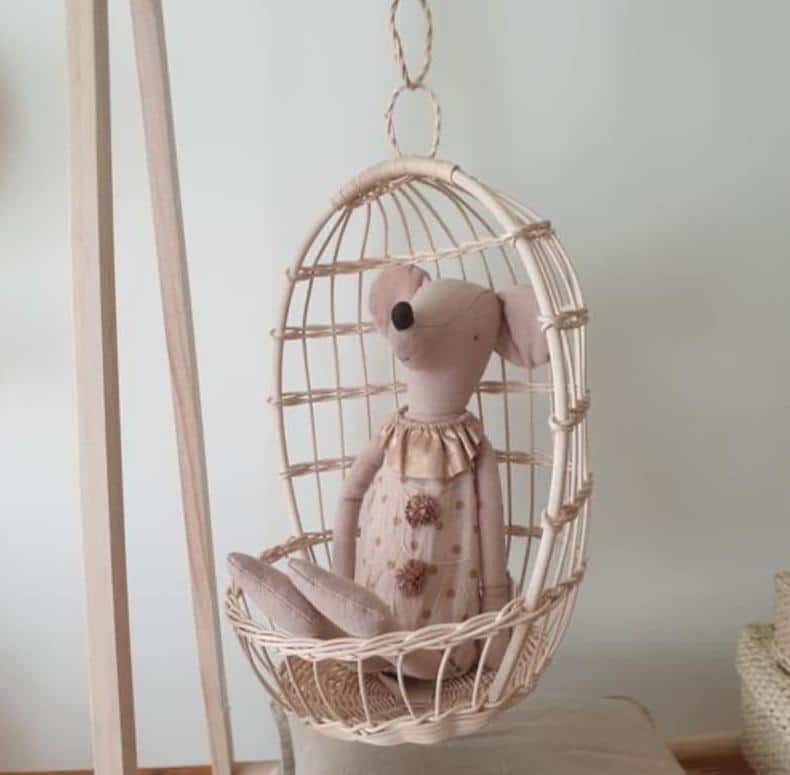 Round hanging rattan birdcage basket holding a plush toy
