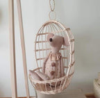 Round hanging rattan birdcage basket holding a plush toy