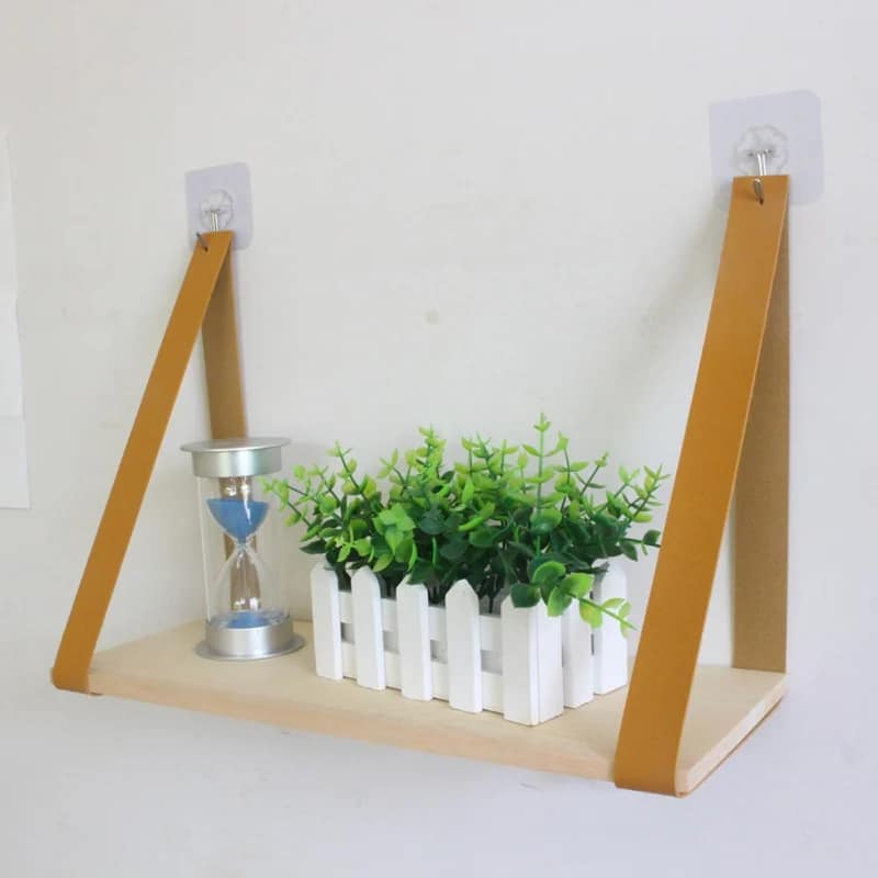 Light wood shelf hanging from two tan faux leather straps