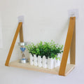 Light wood shelf hanging from two tan faux leather straps