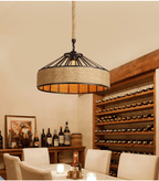 Industrial pendant light with a round black metal frame and a hand woven wicker shade hung by a rope