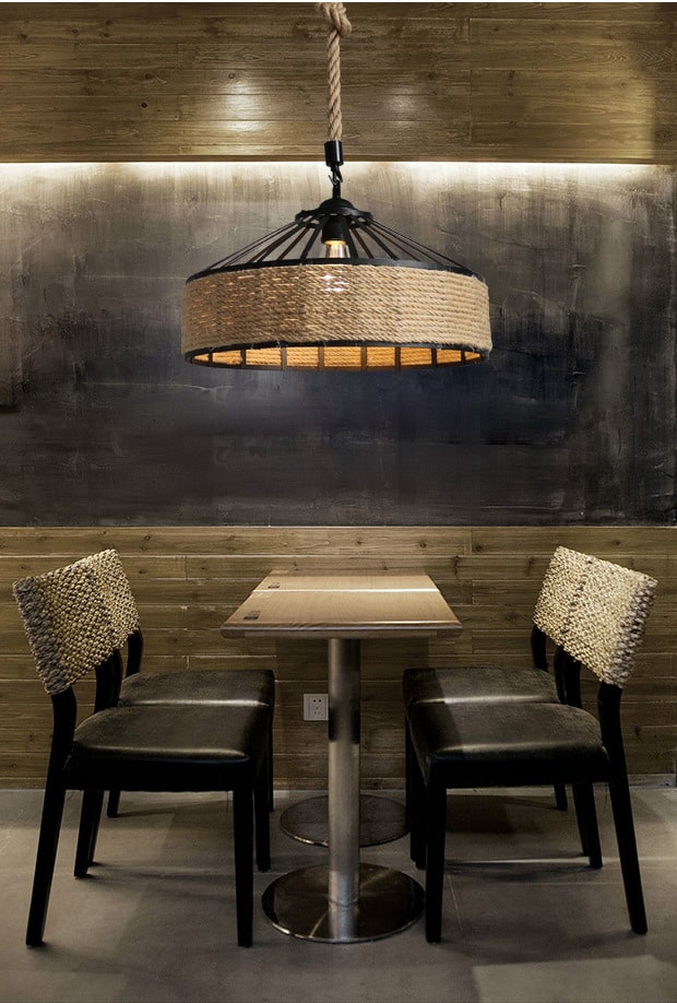 Industrial pendant light with a round black metal frame and a hand woven wicker shade hung by a rope