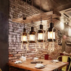 Industrial pendant light with a natural wood branch and four geometric black metal lanterns