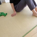 Rolled Japanese rattan mat with a green border and dotted non-slip backing