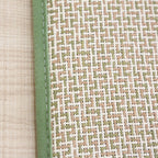 Rolled Japanese rattan mat with a green border and dotted non-slip backing