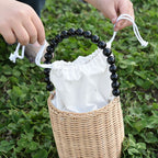 Small woven basket with bead handle and white drawstring liner