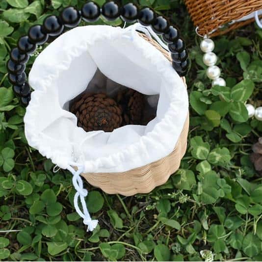 Small woven basket with bead handle and white drawstring liner