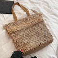 Large brown woven straw shoulder bag with fringe trim