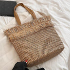 Large brown woven straw shoulder bag with fringe trim