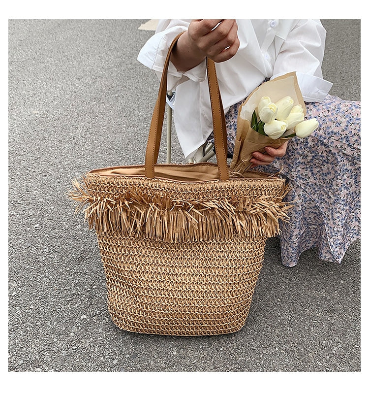 Large brown woven straw shoulder bag with fringe trim