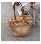 Large brown woven straw shoulder bag with fringe trim
