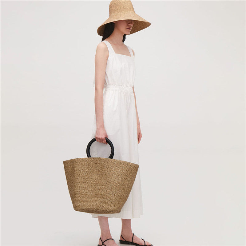 Large oval hand woven rattan handbag with an airy weave and a bamboo toggle