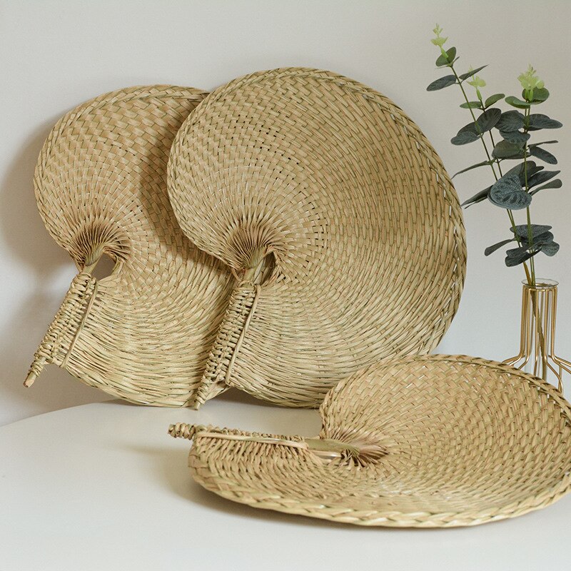 Large round woven fan on a bamboo frame, shown in a group on a console