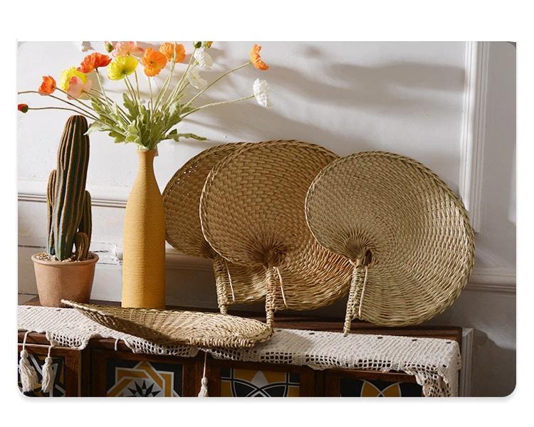 Large round woven fan on a bamboo frame, shown in a group on a console