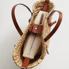 Large brown woven straw handbag with short handles and a camel crossbody strap