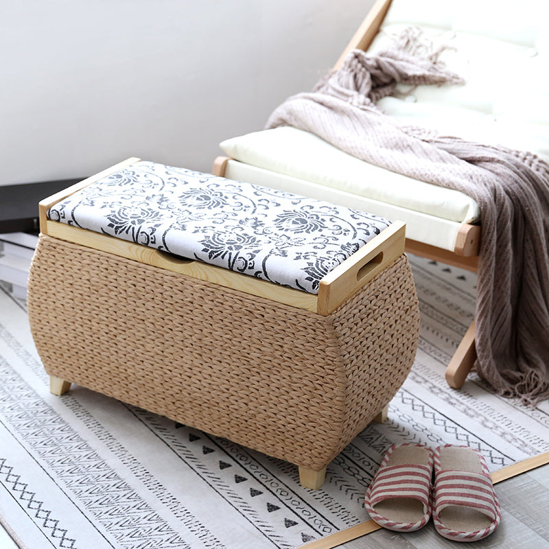 Light woven storage stool with a white and black floral padded lid on turned wood feet