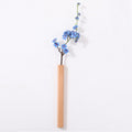 Slim light natural wood wall vase holding a single stem