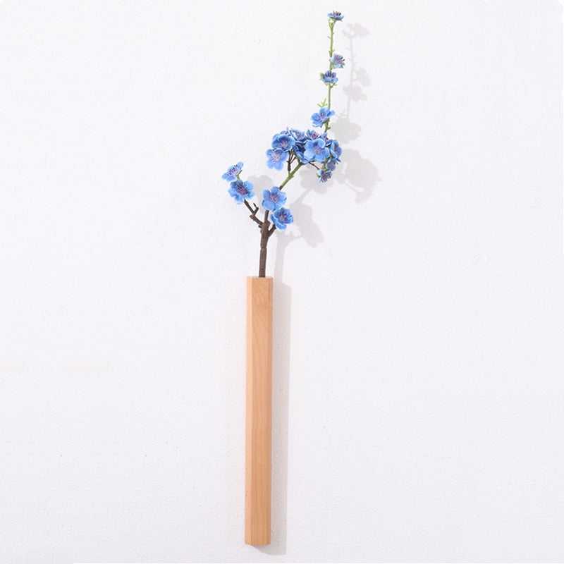 Slim light natural wood wall vase holding a single stem