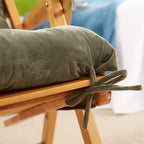 Long deep green polyester cushion covering the seat and back of a chair
