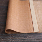 Long honey toned woven bamboo table runner in a Japanese style