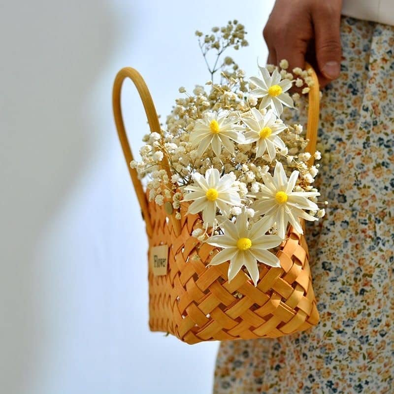 Three mini woven flower baskets with handles and flowers