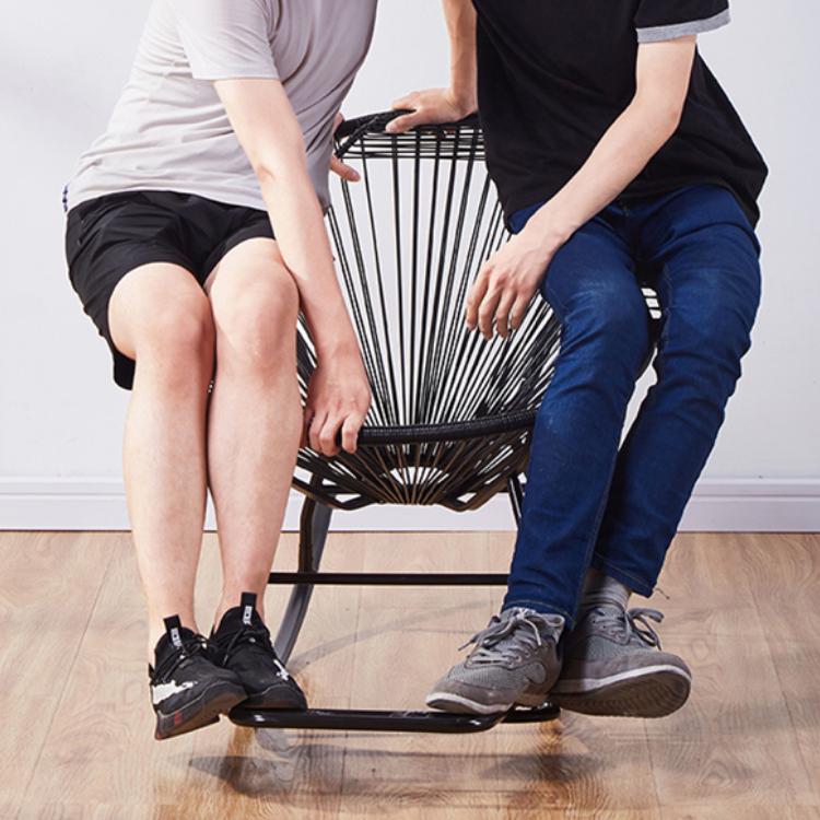 Modern rocking chair hand woven in black rattan with generous curves