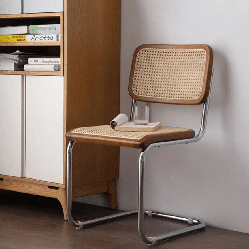 Modern chair with a high, tightly woven rattan back on a stainless steel frame