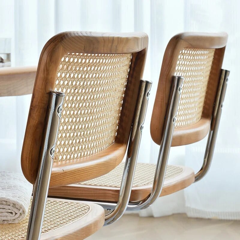 Modern chair with a high, tightly woven rattan back on a stainless steel frame