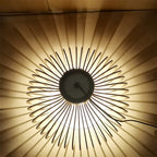 Modern geometric chandelier with light wood slats on a slim black metal frame