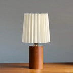 Modern bedside lamp with a shaped brown wood base and a fabric shade