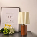 Modern bedside lamp with a shaped brown wood base and a fabric shade