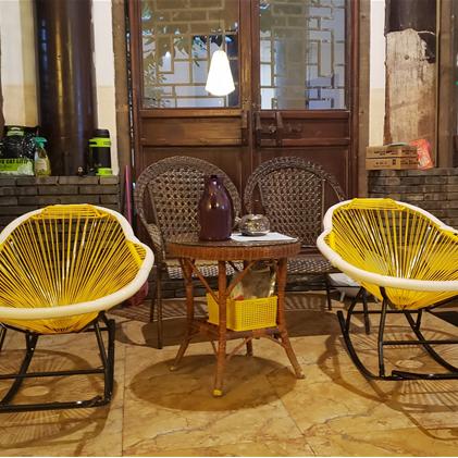 Modern rocking chair hand woven in sunny yellow rattan with generous curves