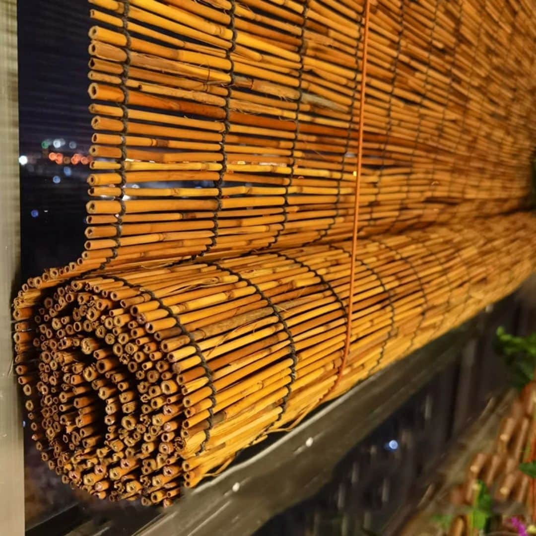 Roll up blind made of round natural stems tied with cord, rolled at the bottom