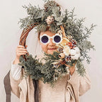 Natural wicker wreath base shown decorated with greenery and dried orange slices