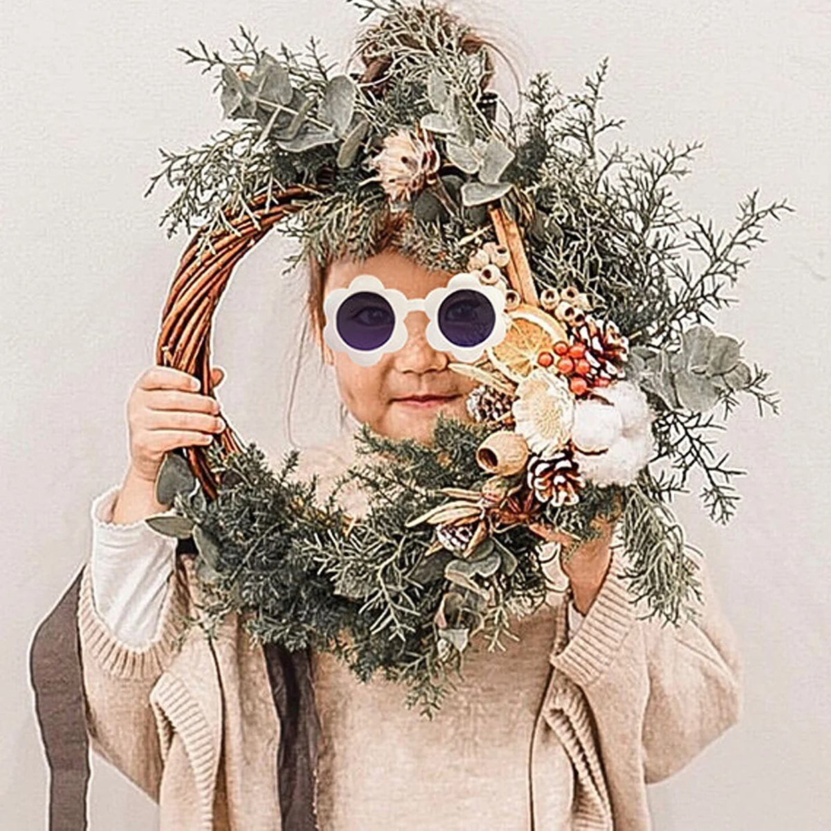 Natural wicker wreath base shown decorated with greenery and dried orange slices