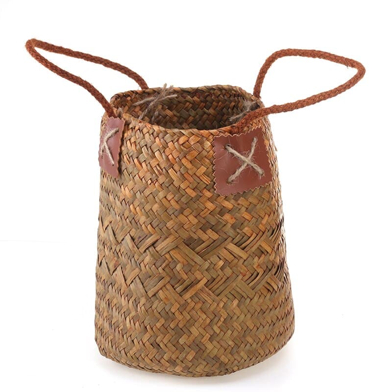 Two tall natural woven baskets with leather handles, one with flowers
