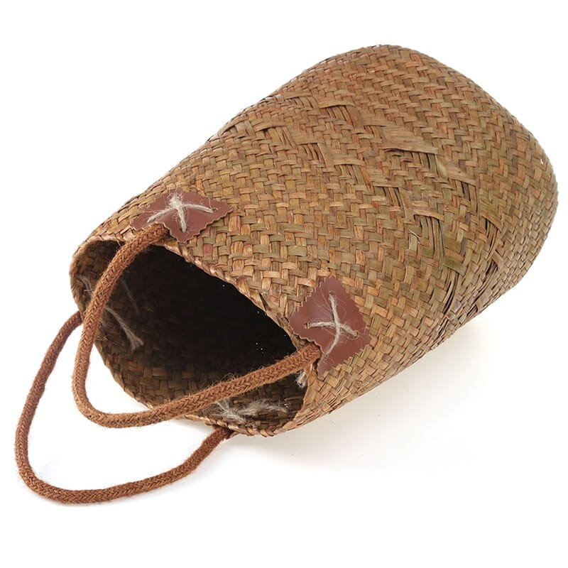 Two tall natural woven baskets with leather handles, one with flowers