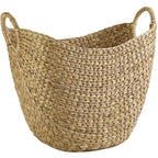 Wide natural woven laundry basket with handles holding throws