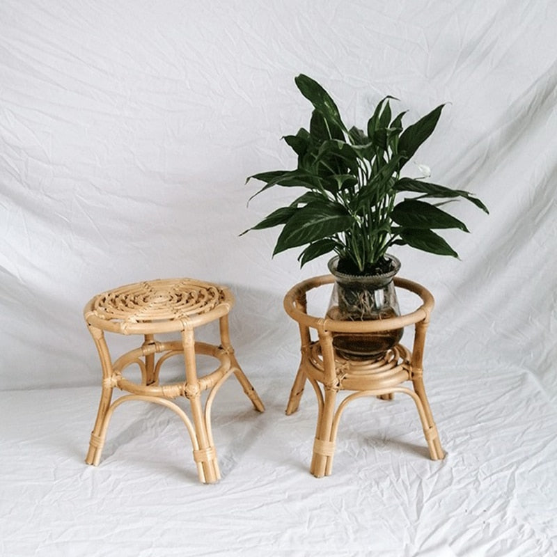 Hand woven natural rattan plant stand holding a potted plant