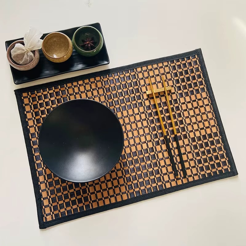 Rectangular woven bamboo placemat with a two tone beige and black checkered pattern